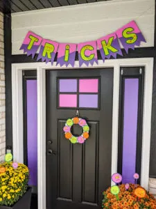 DIY Halloween banner that spells TRICKS with haunted monster eyes, stitched mouths, and shredded bunting from monster claws.