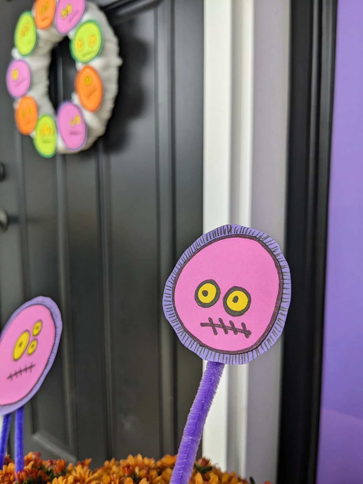 DIY Halloween floral picks with a silly monster faces in mums with a DIY monster wreath on the front door