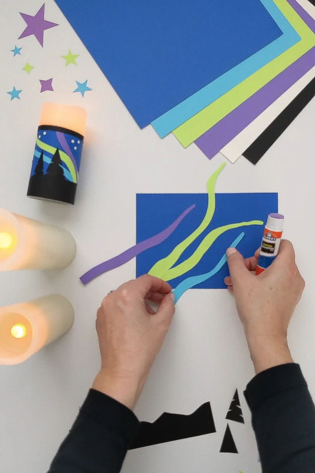 Gluing paper onto a Northern Lights candle wrap craft