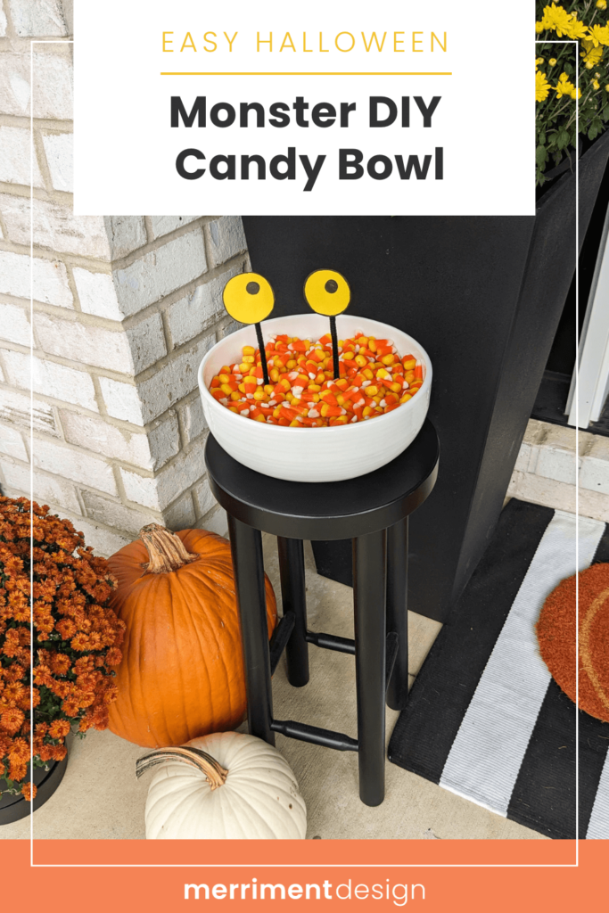 Halloween candy bowl with monster eyes filled with candy corn on a front porch with pumpkins and mums