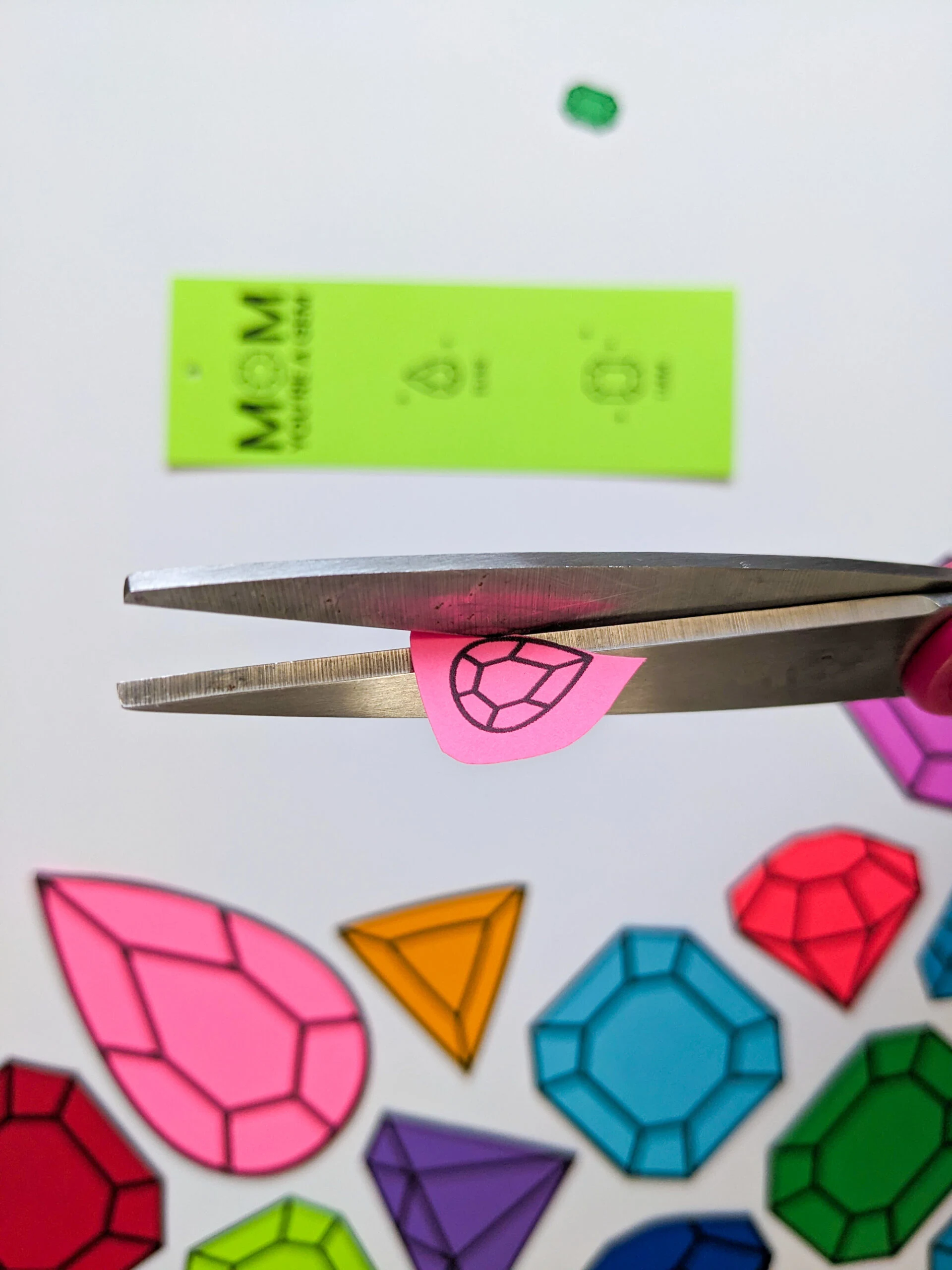 Cutting out paper gems with scissors to make DIY birthstone gifts for mom and grandma