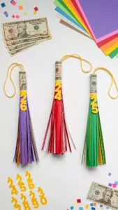 Three big paper graduation tassels with cash rolled inside for a money graduation gift