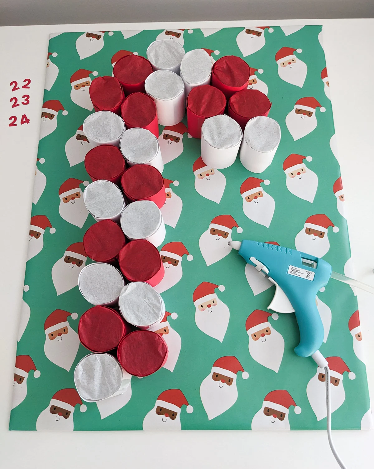 Using a glue gun to glue together a candy cane DIY advent calendar