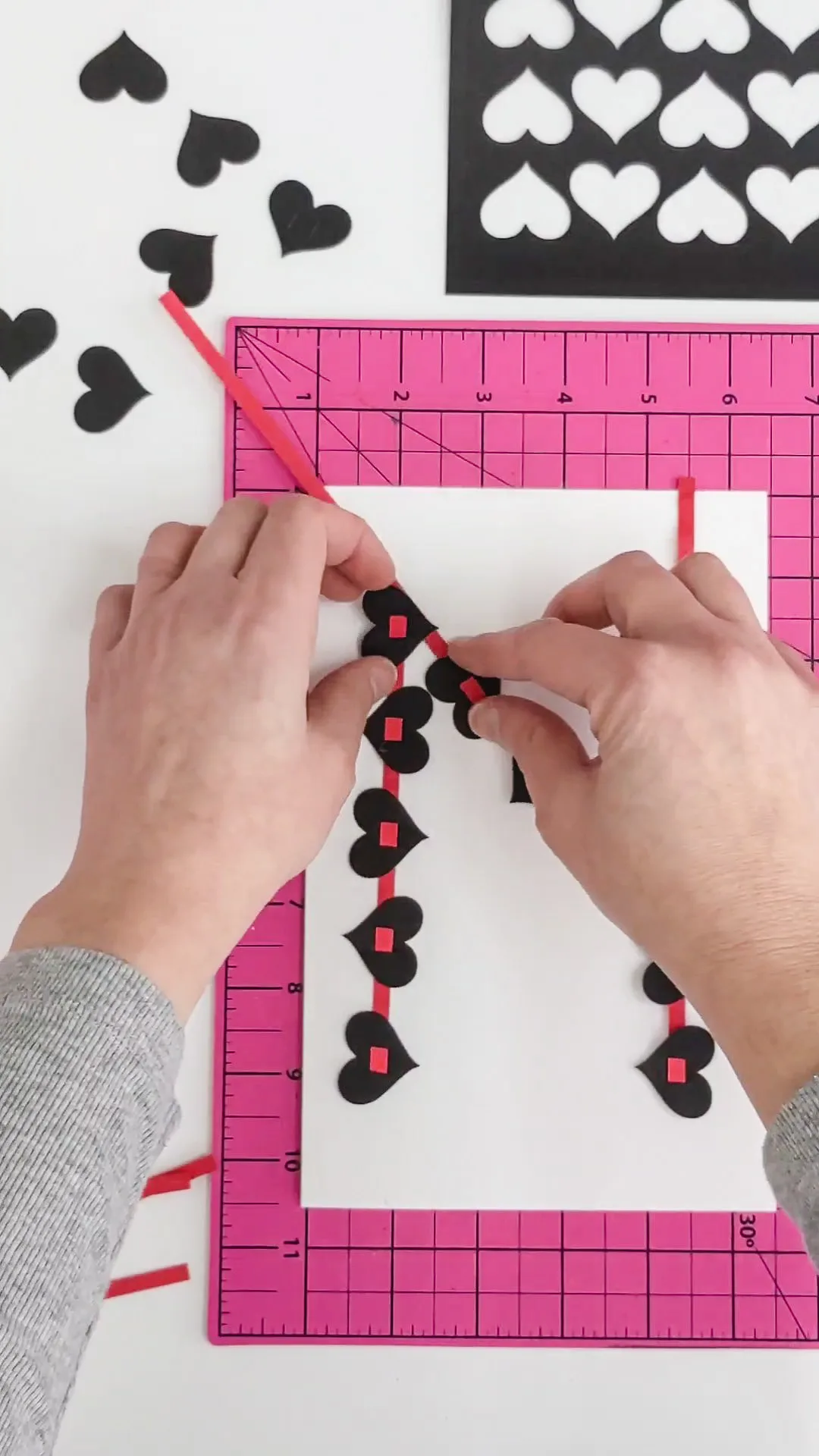 Gluing black hearts onto a DIY Valentine's Day card