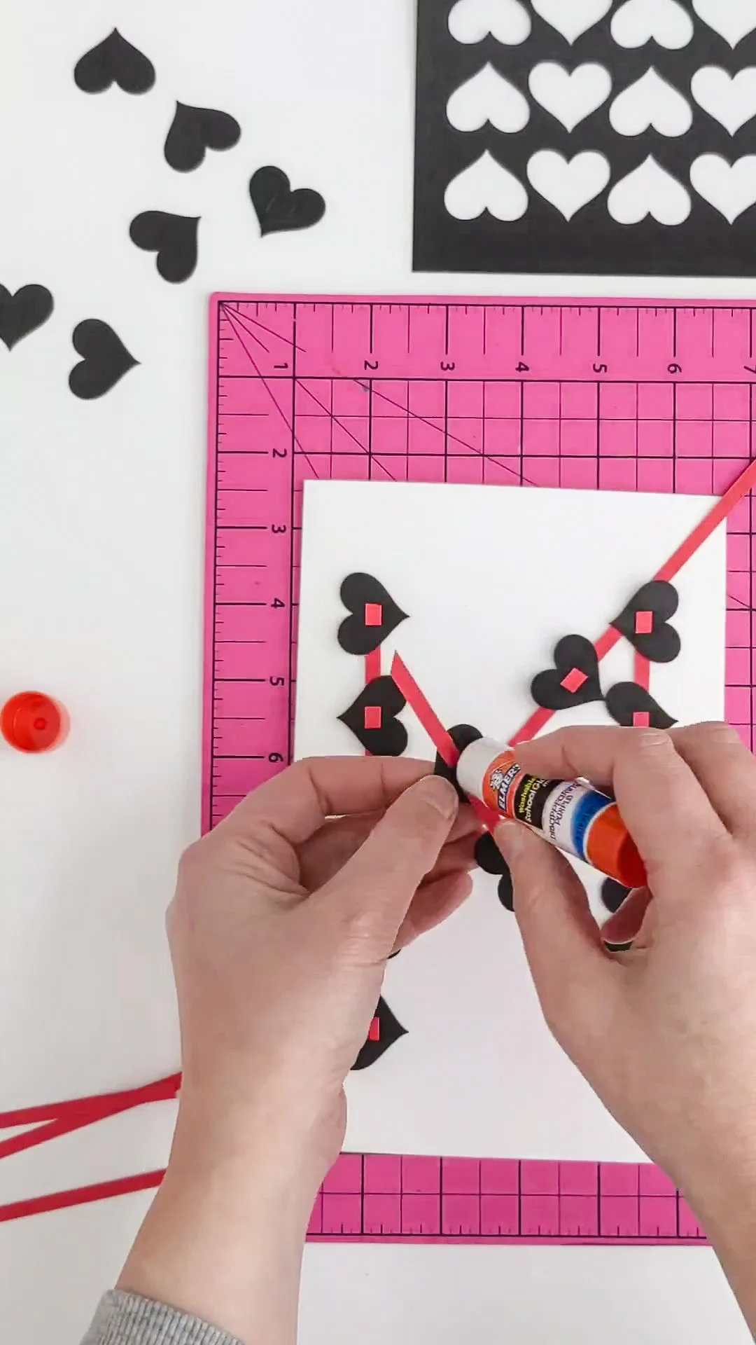 Gluing black hearts onto a DIY Valentine's Day card