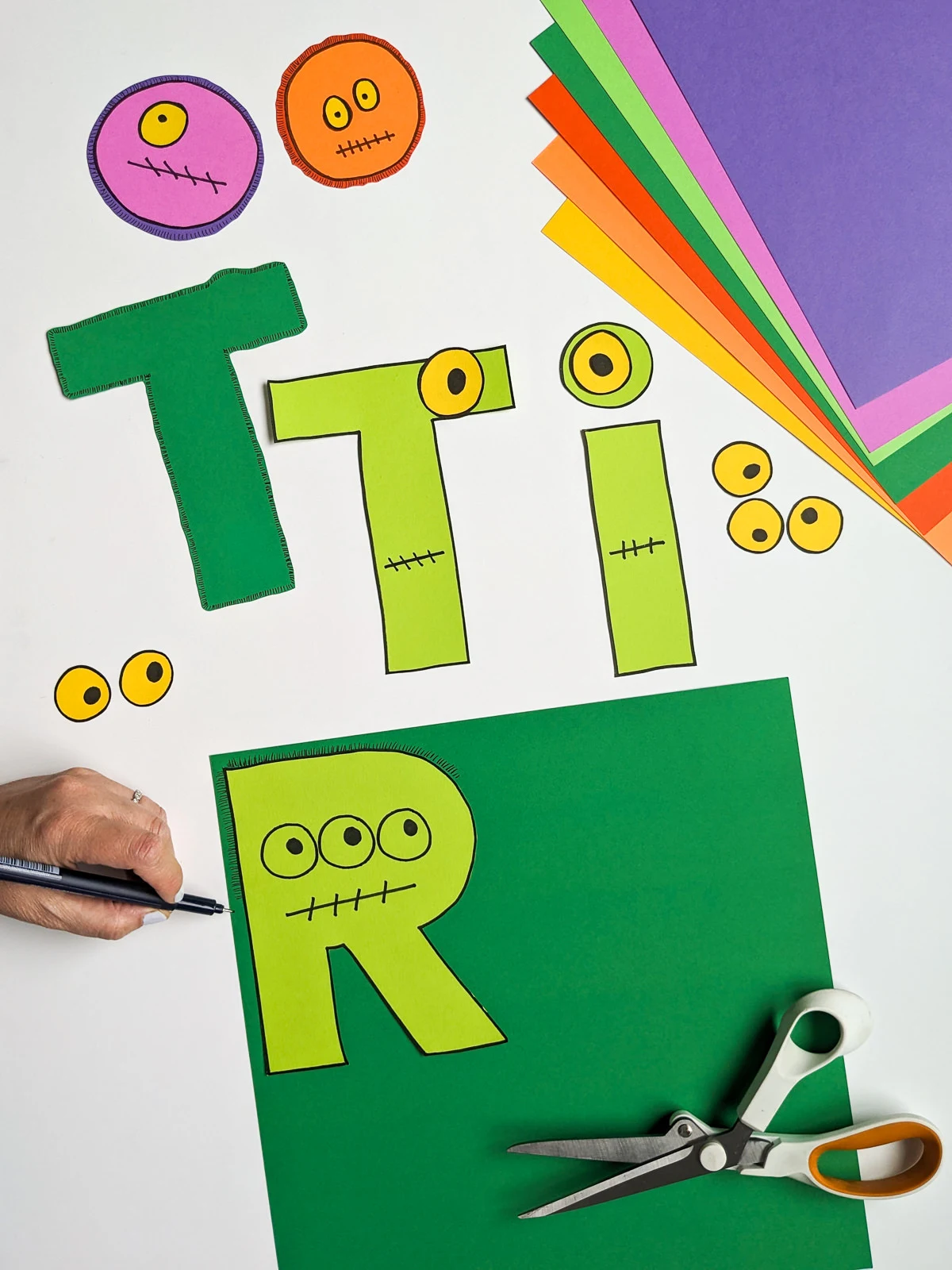 DIY Halloween banner craft that spells Tricks. Each letter has monster eyes and fuzzy fur around it.