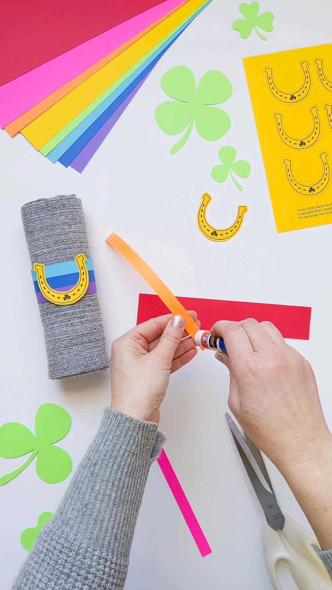 Gluing DIY rainbow napkin rings for the St. Patrick's Day dinner table